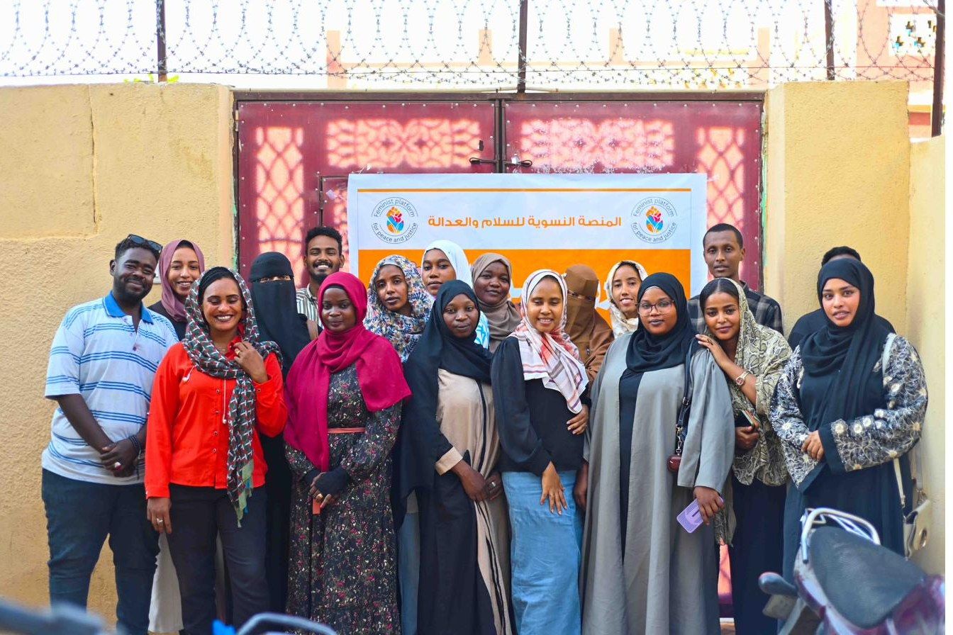 The team standing together in front of the organization's banner outside a community building