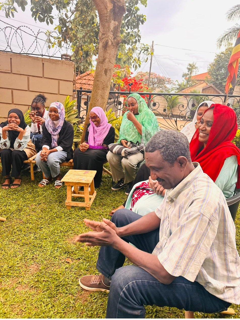 A community session held outdoors under a tree, with participants seated in a circle