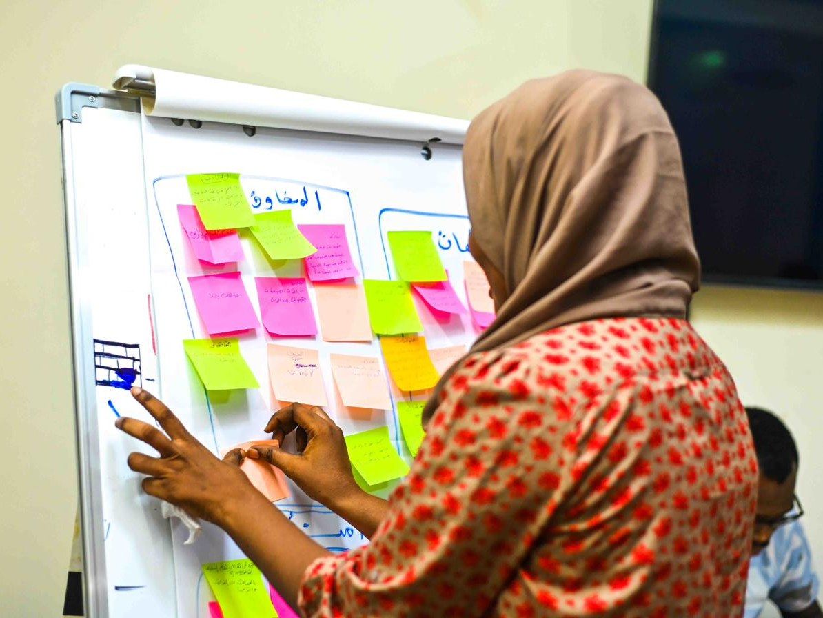 A participant arranging coloured notes across a workshop board